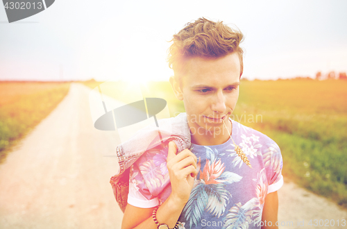 Image of sad young hippie man walking along country road