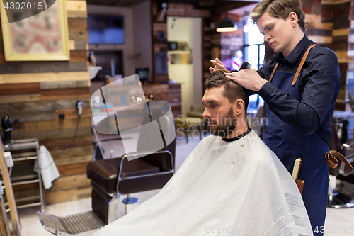 Image of man and barber cutting hair at barbershop