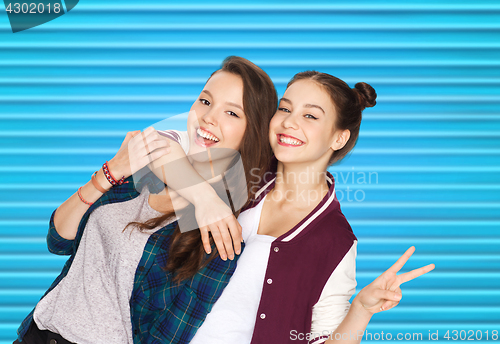 Image of happy teenage girls hugging and showing peace sign