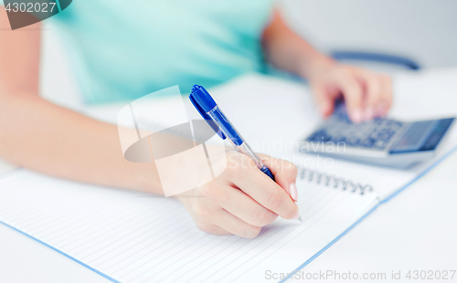 Image of businesswoman working with calculator in office