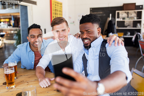 Image of friends taking selfie and drinking beer at bar