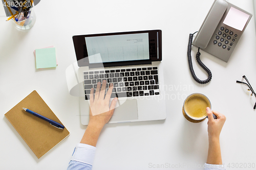 Image of businesswoman with laptop and coffee at office