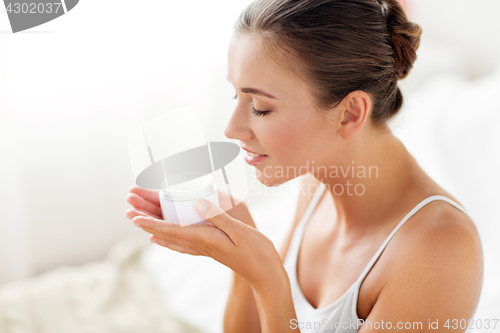 Image of close up of happy woman holding and smelling cream