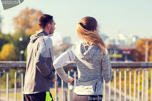 Image of happy couple running outdoors