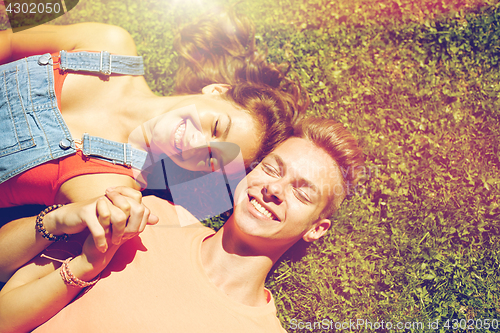 Image of happy teenage couple lying on grass at summer
