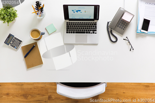 Image of laptop, phone and other office stuff on table