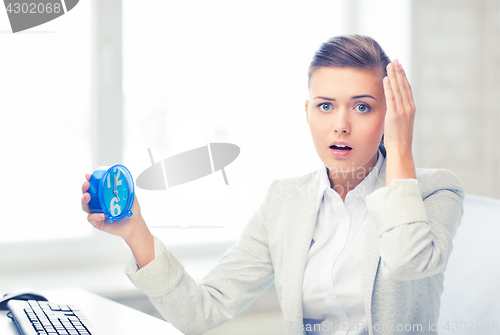 Image of stressed businesswoman holding clock