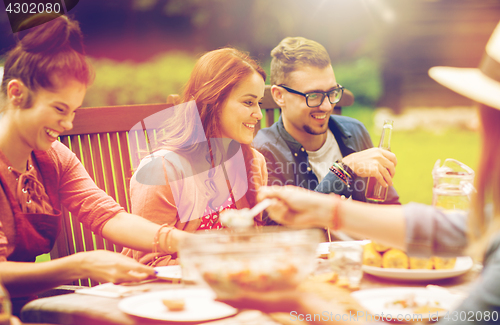 Image of happy friends having dinner at summer garden party