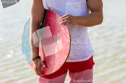 Image of close up of man with skimboard on summer beach