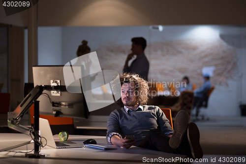 Image of businessman sitting with legs on desk at office