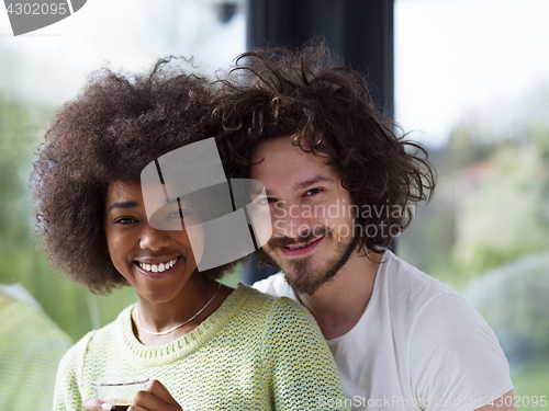 Image of happy multiethnic couple relaxing at modern home indoors