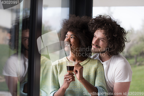 Image of happy multiethnic couple relaxing at modern home indoors