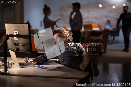 Image of businessman sitting with legs on desk at office
