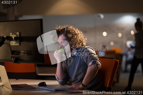 Image of man eating apple in his office