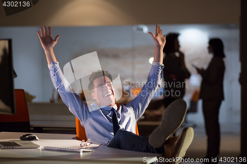 Image of businessman sitting with legs on desk at office