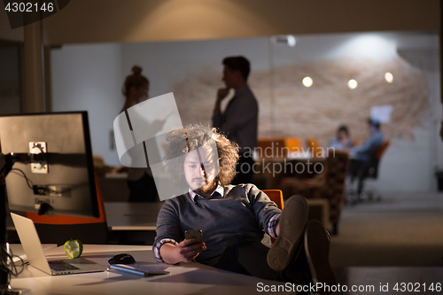 Image of businessman sitting with legs on desk at office