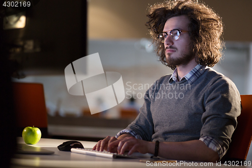 Image of man working on computer in dark office