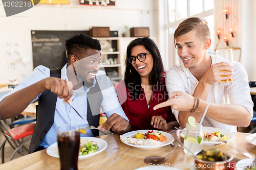 Image of happy friends eating and having fun at restaurant