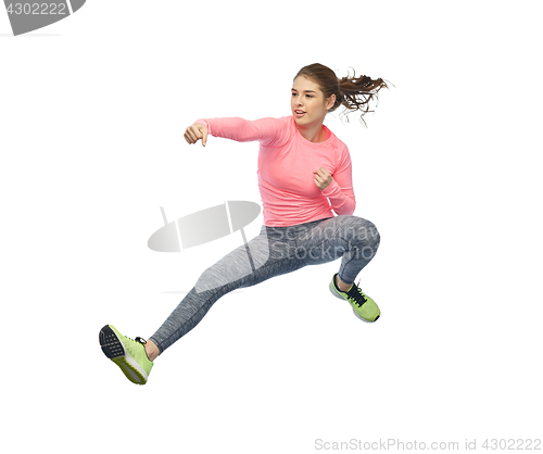 Image of happy sporty young woman jumping in fighting pose