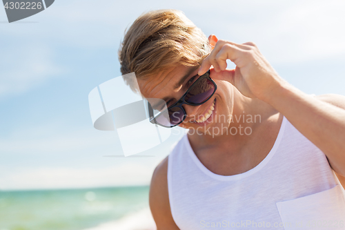Image of smiling young man in sunglasses on summer beach