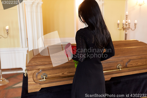 Image of woman with red roses and coffin at funeral