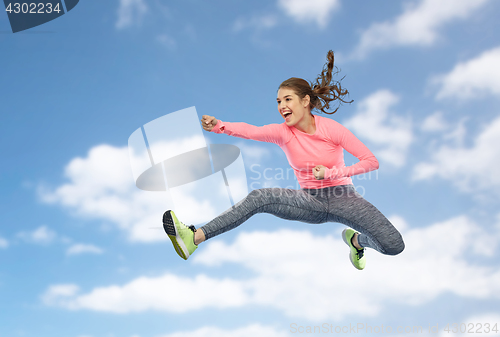 Image of happy sporty young woman jumping in fighting pose