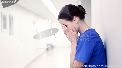 Image of sad or crying female nurse at hospital corridor