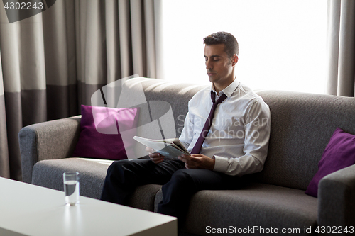 Image of businessman reading newspaper at hotel room