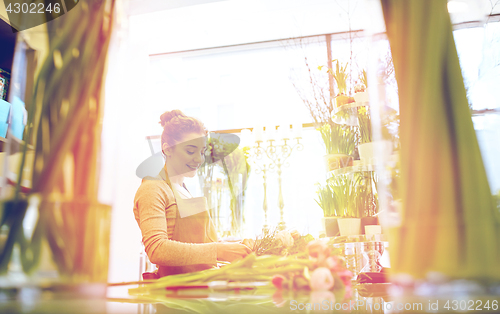 Image of smiling florist woman making bunch at flower shop