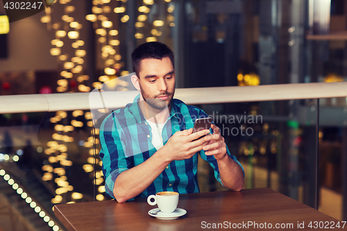 Image of man with smartphone and coffee at restaurant