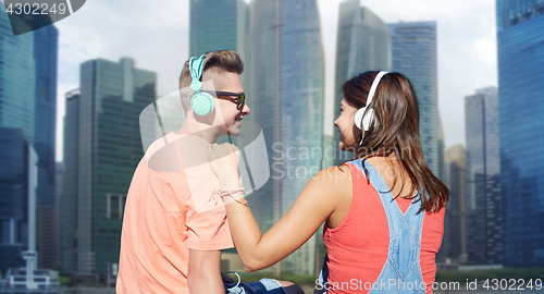 Image of teenage couple with headphones on river berth