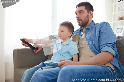 Image of father and son with remote watching tv at home