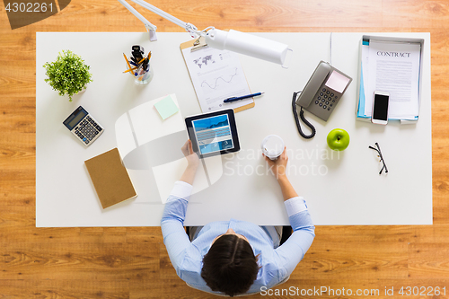 Image of businesswoman with tablet pc and coffee at office