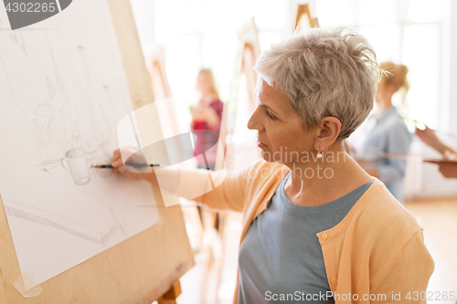 Image of woman artist with pencil drawing at art school