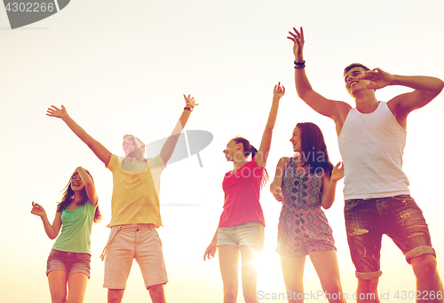 Image of smiling friends dancing on summer beach