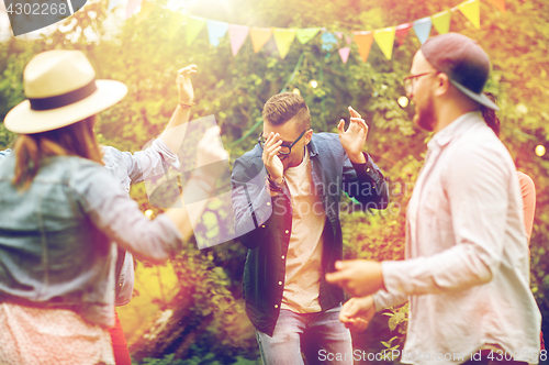 Image of happy friends dancing at summer party in garden