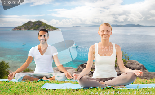 Image of happy couple making yoga exercises outdoors