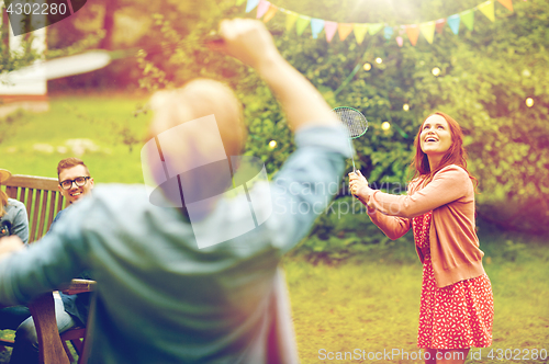 Image of happy friends playing badminton at summer garden