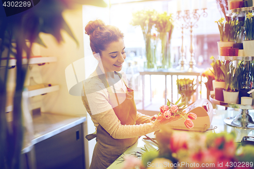 Image of smiling florist woman making bunch at flower shop