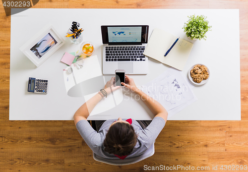 Image of woman with smartphone and laptop at office table