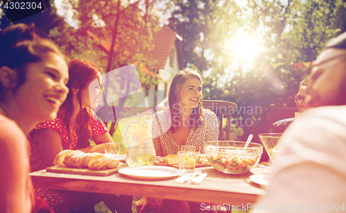 Image of happy friends having dinner at summer garden party