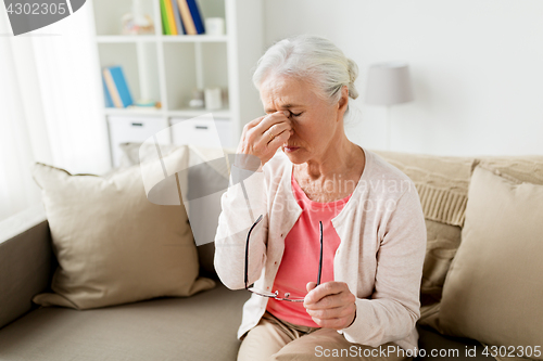 Image of senior woman with glasses having headache at home