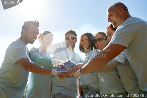 Image of group of volunteers putting hands on top outdoors