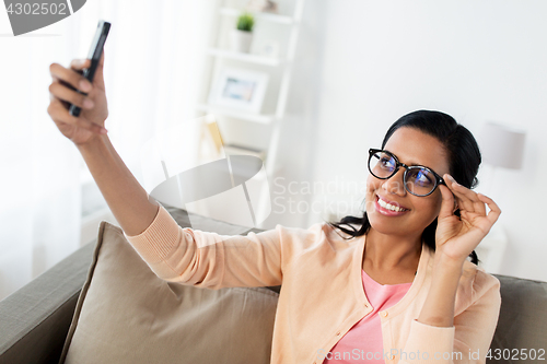 Image of happy woman taking selfie with smartphone at home