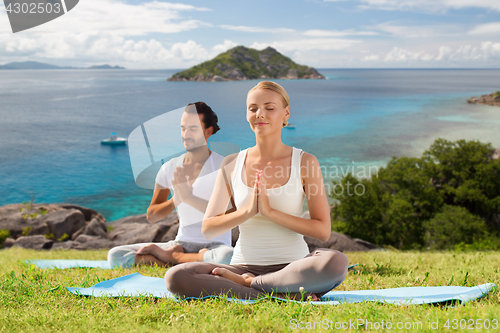 Image of happy couple doing yoga and meditating outdoors