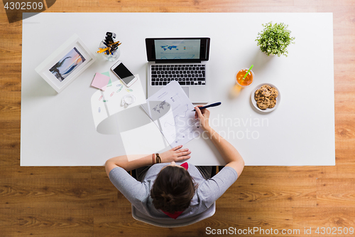 Image of woman with laptop and papers at office table