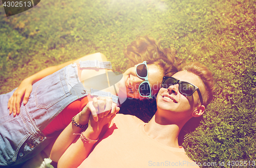 Image of happy teenage couple lying on grass at summer