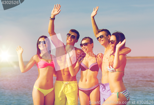 Image of smiling friends in sunglasses on summer beach