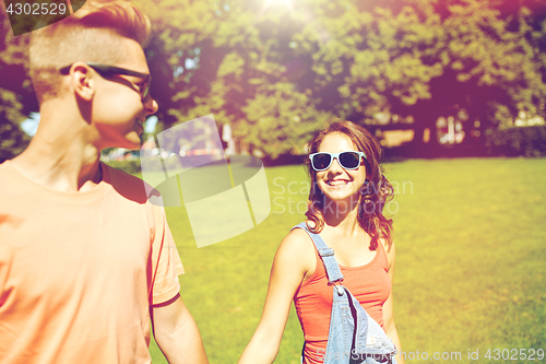 Image of happy teenage couple walking at summer park