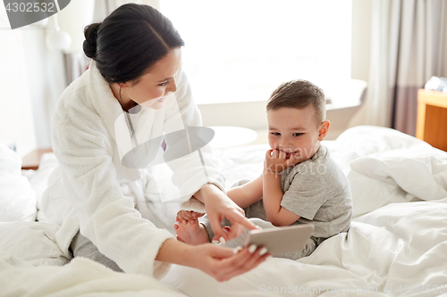 Image of mother and son with smartphone in bed at hotel